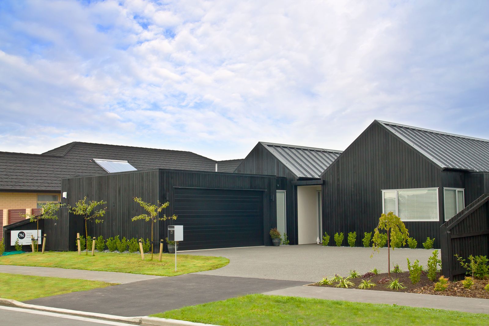 White insulated sectional garage door on a stone-clad home — wholesale from Sunotech China